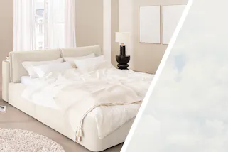 Minimalistisch eingerichtetes Schlafzimmer mit einem weissen Bett in voluminösem, cremeweissem Cordstoff und vielen luftigen Textilien; daneben ein Bild von einem Himmel mit weissen Wölkchen.
