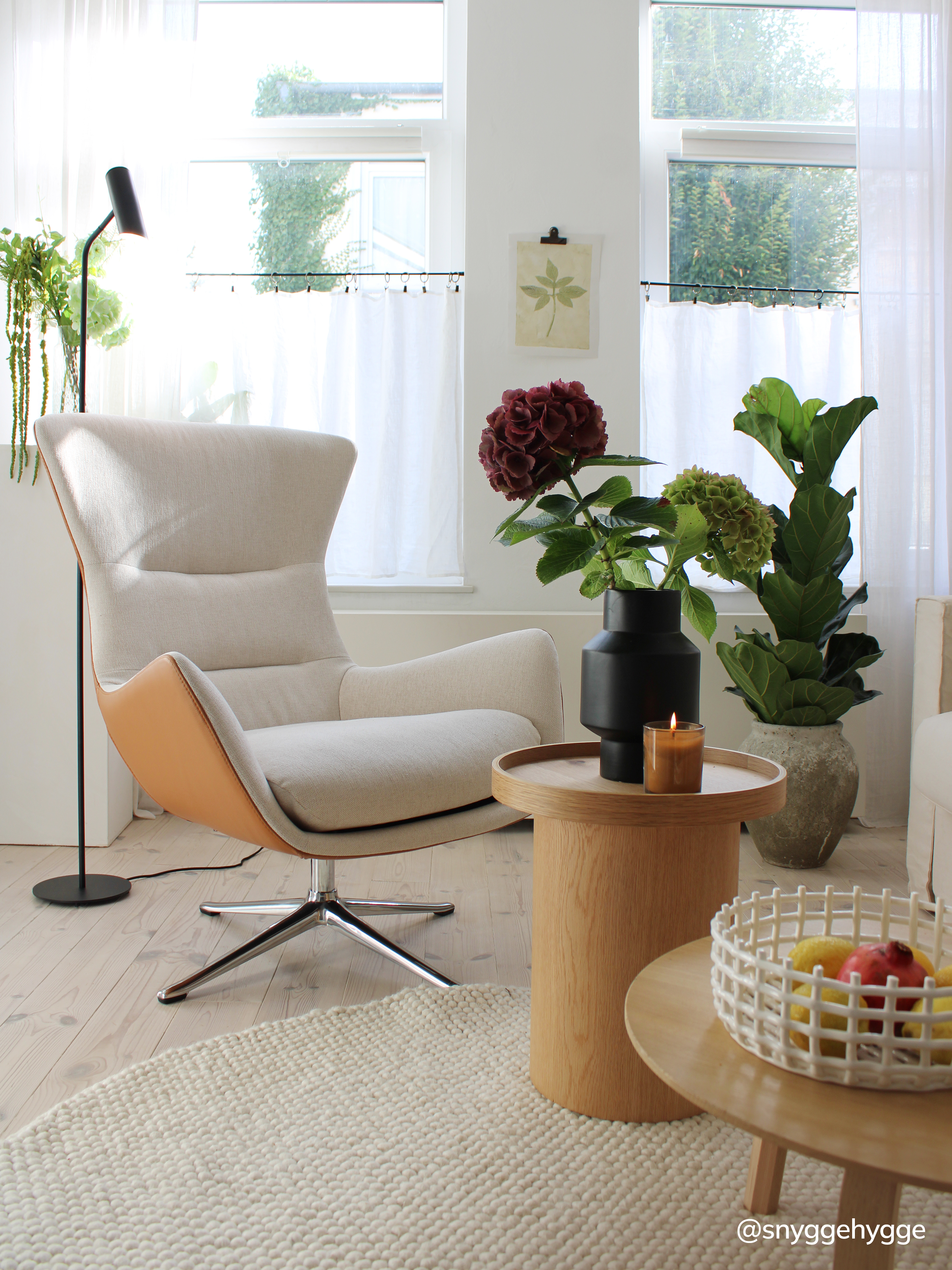 Beiger Drehsessel mit Beistelltisch aus Holz mit Pflanzen.