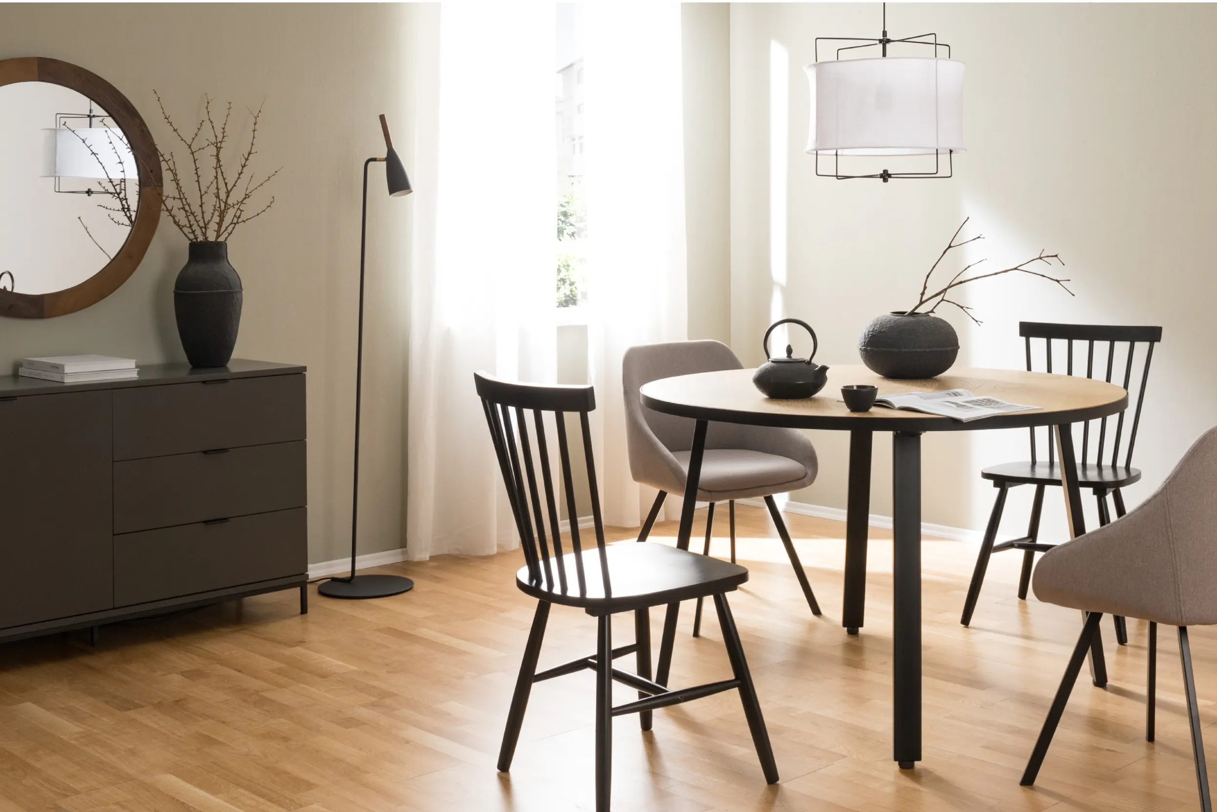 Photo d'un coin repas avec une table ronde, quatre chaises, des objets décoratifs, le tout avec des tons naturels et chauds