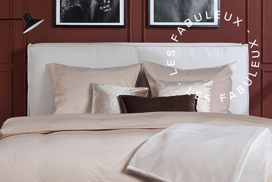 Chambre avec mur marron chocolat et tapis beige, lit capitonné et draps de couleur crème, coussin marron ; photo de différentes tablettes de chocolat faisant office de nuancier marron.