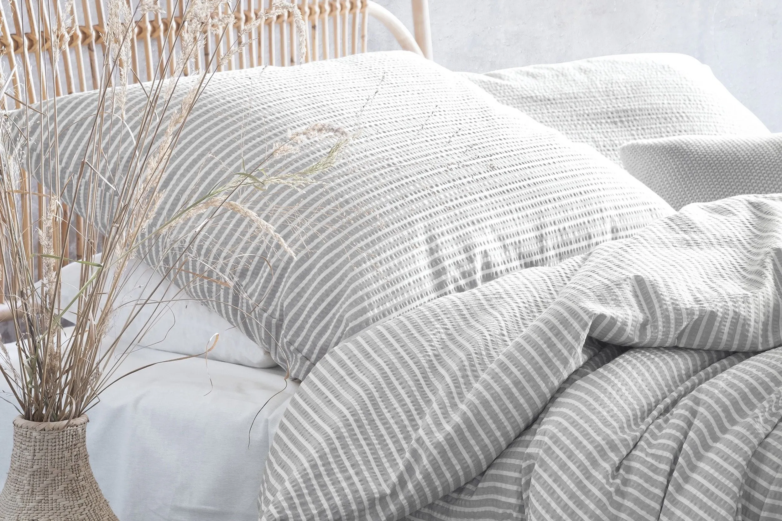 Luftige gestreifte Seersucker-Bettwäsche auf einem Rattanbett