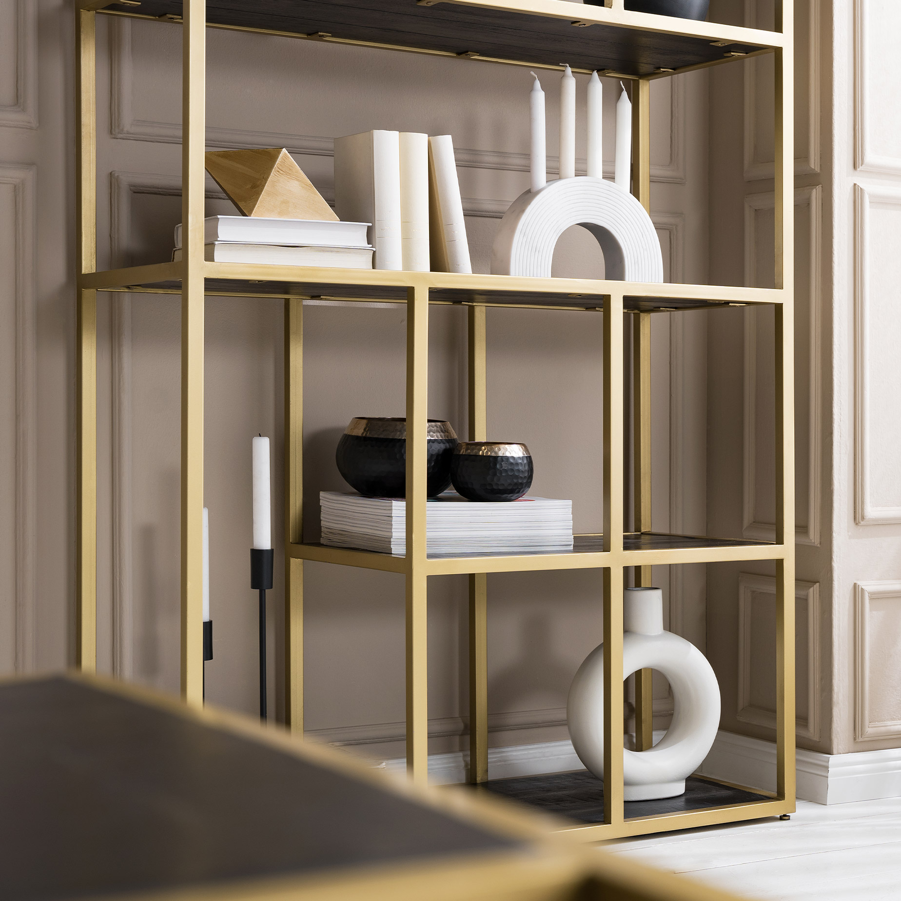 Étagère avec plateaux en bois noir, structure en métal doré, vase et bougeoir en arc de cercle blancs, coupes décoratives et bougeoir noirs