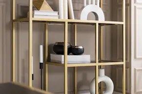 Étagère avec plateaux en bois noir, structure en métal doré, vase et bougeoir en arc de cercle blancs, coupes décoratives et bougeoir noirs
