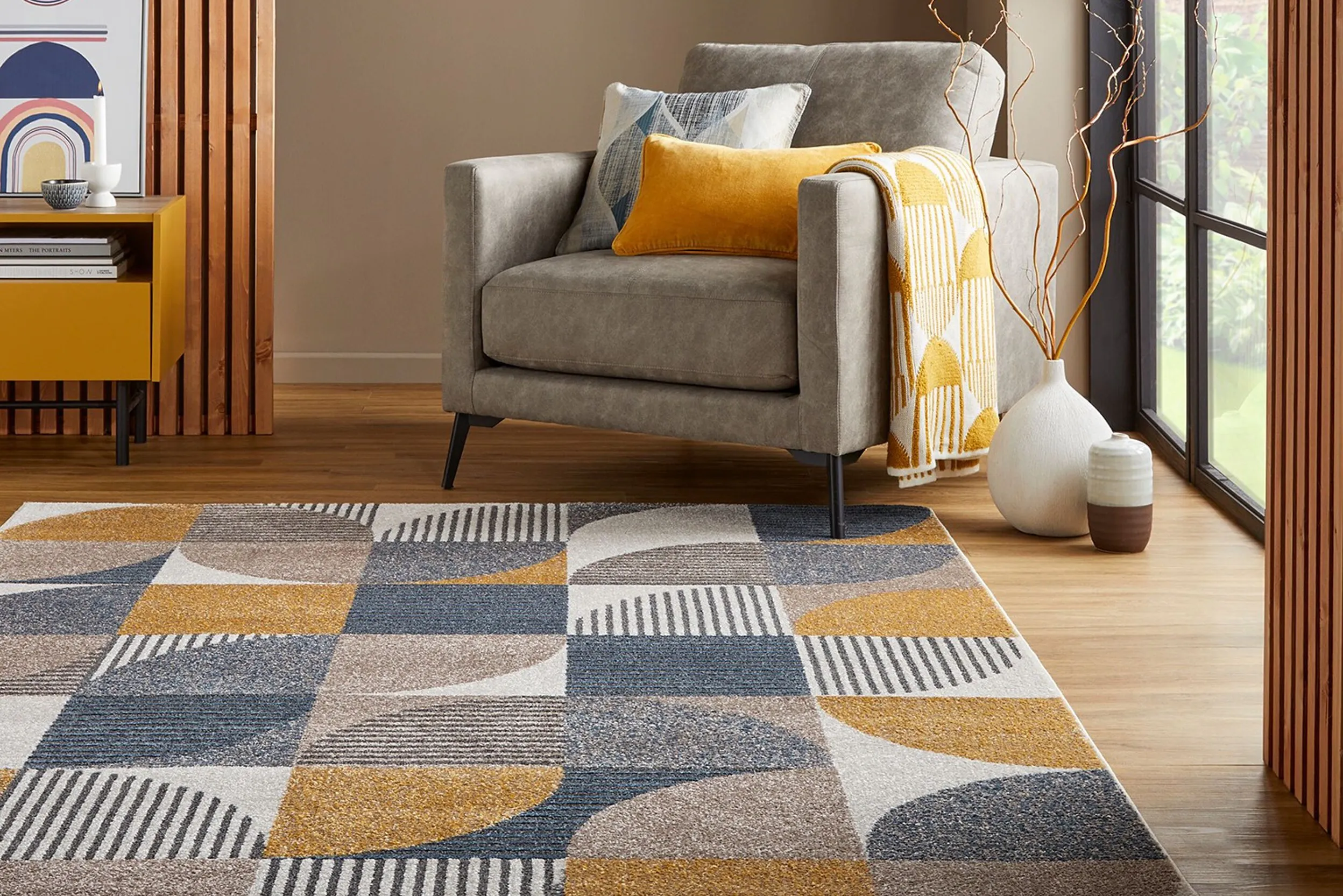 Un tapis à poils courts gris, jaune, blanc, noir et gris dans un salon, avec un fauteuil dans le coin