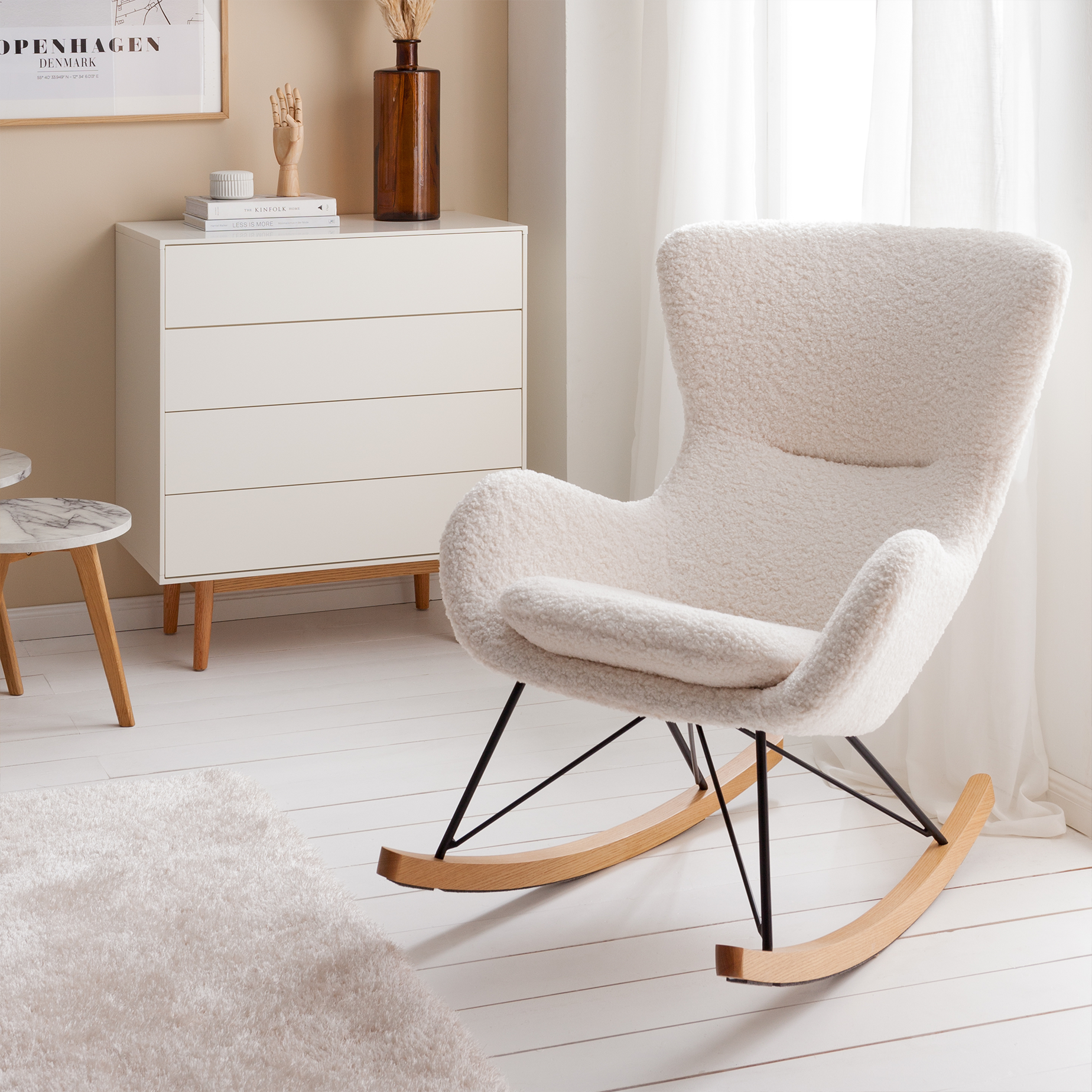 Fauteuil à bascule tendance avec tissu bouclé beige et patins en bois dans une pièce aux couleurs claires.