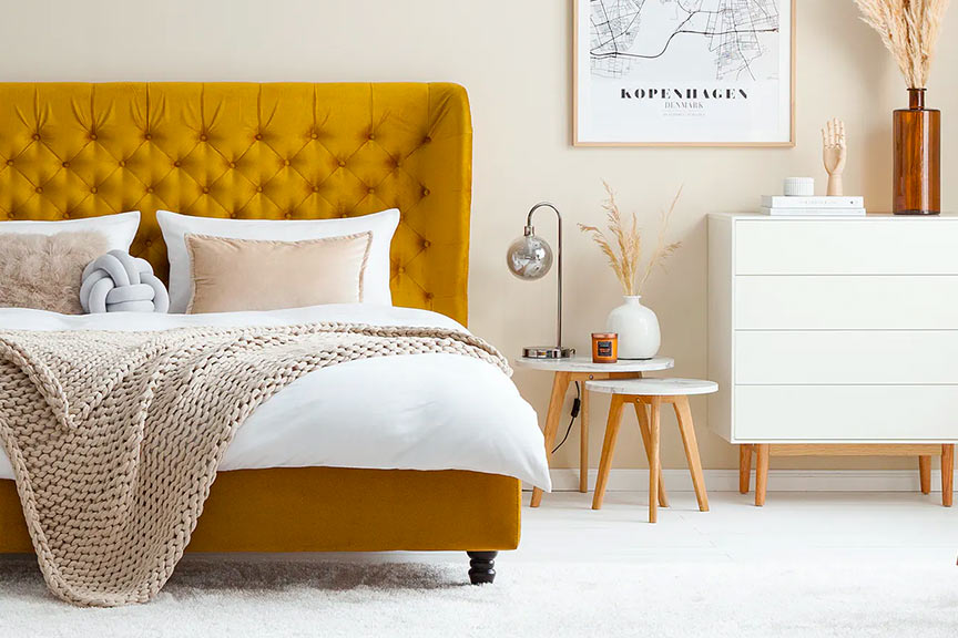 Schlafzimmer im Skandi-Stil vor Samtbett in Senfgelb