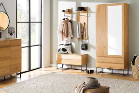 Einladender, heller Eingangsbereich mit zahlreichen Stauraumlösungen wie Garderobenpaneelen, Kleider- und Schuhschrank; Teppich, Spiegel und Tischlampe für eine wohnliche Atmosphäre.