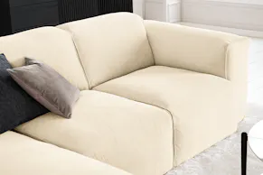 Canapé en velours côtelé blanc cassé Studio Copenhagen, avec un coussin en velours ras gris souris et un coussin en tissu structuré noir.