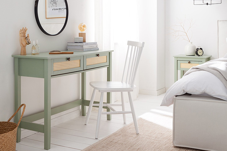 Console vert sauge de la série Belleria par Maison Belfort, avec façades des tiroirs en cannage, combinée avec une chaise scandinave blanche.