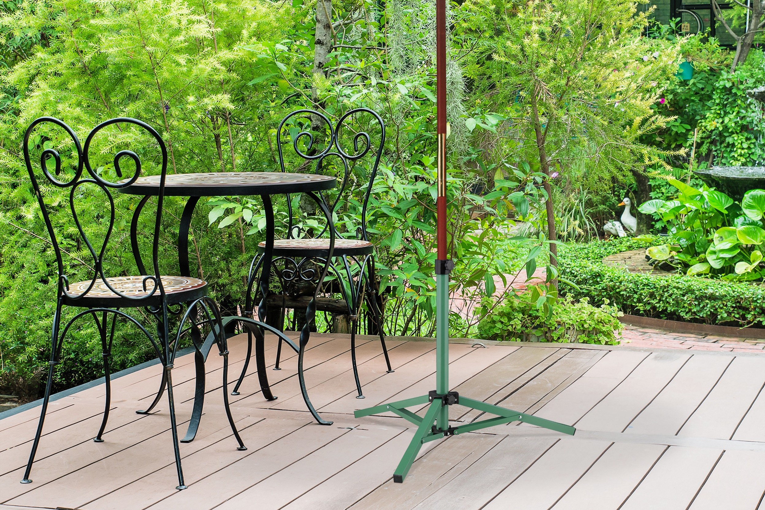 Zusammenklappbarer Sonnenschirmstaender in Gruen auf einer Terrasse neben einem Bistro-Set