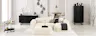 Salon noir et blanc avec canapé blanc Hudson de chez Studio Copenhagen sur un tapis fluffy blanc, avec meubles noirs posés devant des murs blancs et présentant des objets déco noirs et blancs.