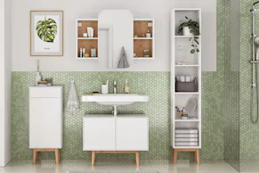 Meubles de salle de bain blancs de style scandinave devant un papier peint vert.