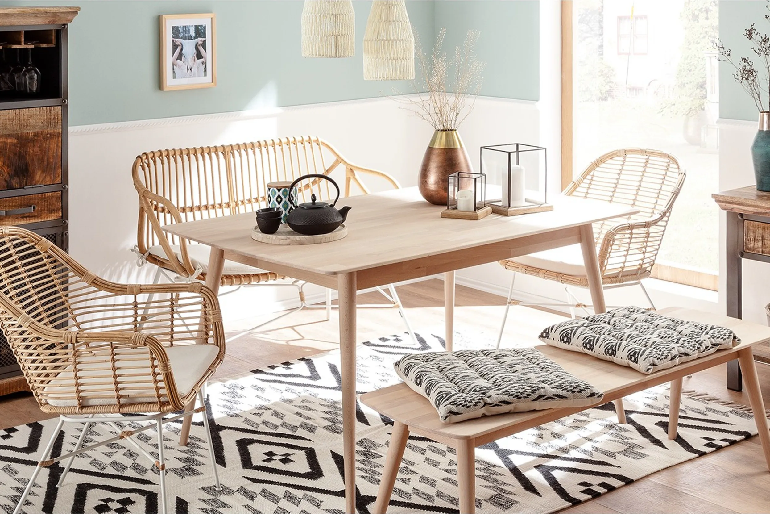 Heller und freundlicher Essbereich mit Tisch, Rattanbank, Rattan-Armlehnstühlen und Holzbank