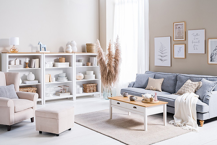 Salon de style campagnard avec canapé bleu clair, fauteuil beige ainsi que table basse et étagère mêlant blanc et bois, de la série Rivery par Maison Belfort.
