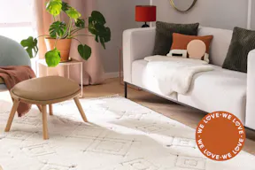 Gemütliches Wohnzimmer, im Mittelpunkt ein hellbeiger Teppich mit dezenten Rautenmustern.