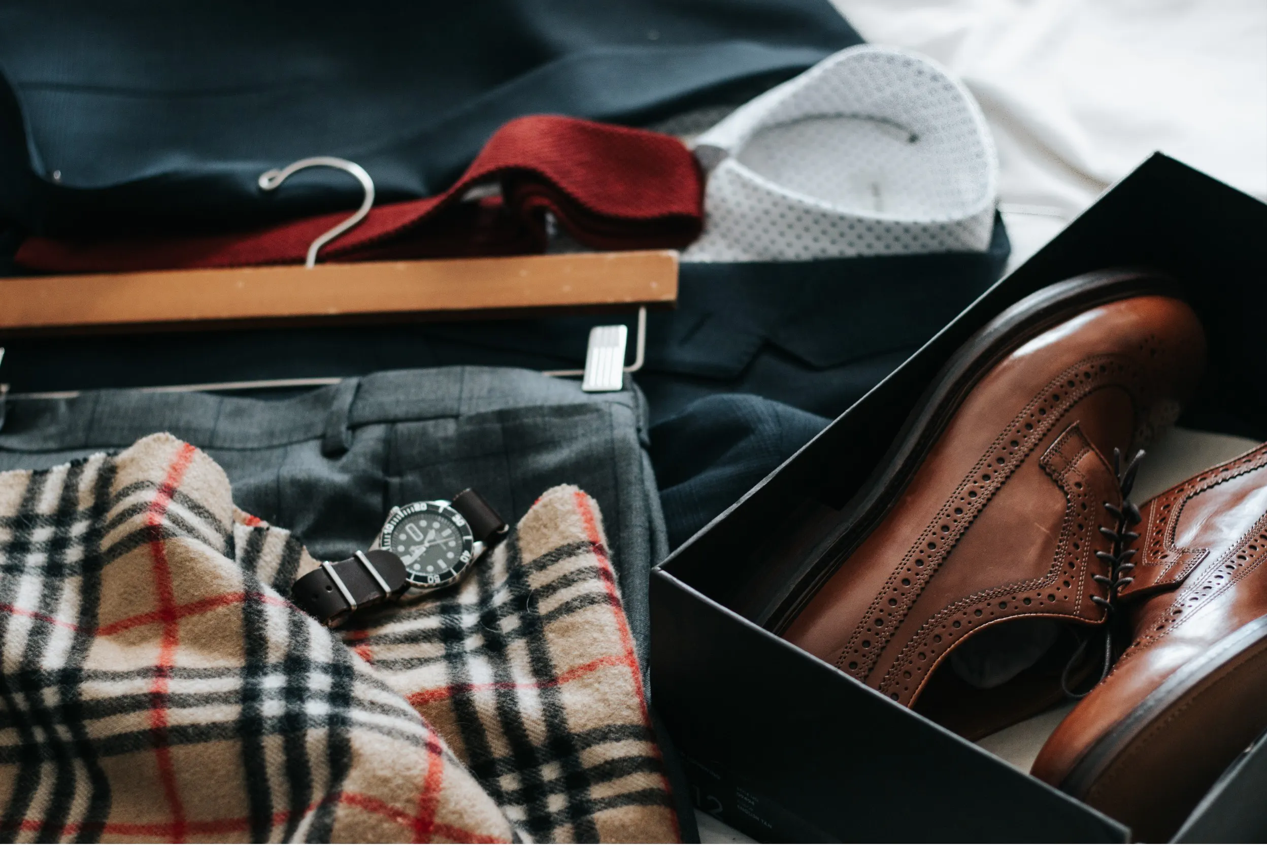 Schal, Uhr, offener Schuhkarton mit Schuhen sowie Anzug auf dem Bett ausgebreitet