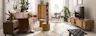 Wohnzimmer im Boho-Style mit einem Ledersofa, Holzmöbeln mit Wiener Geflecht, Rattan, vielen Pflanzen, Textilien und Deko aus Messing