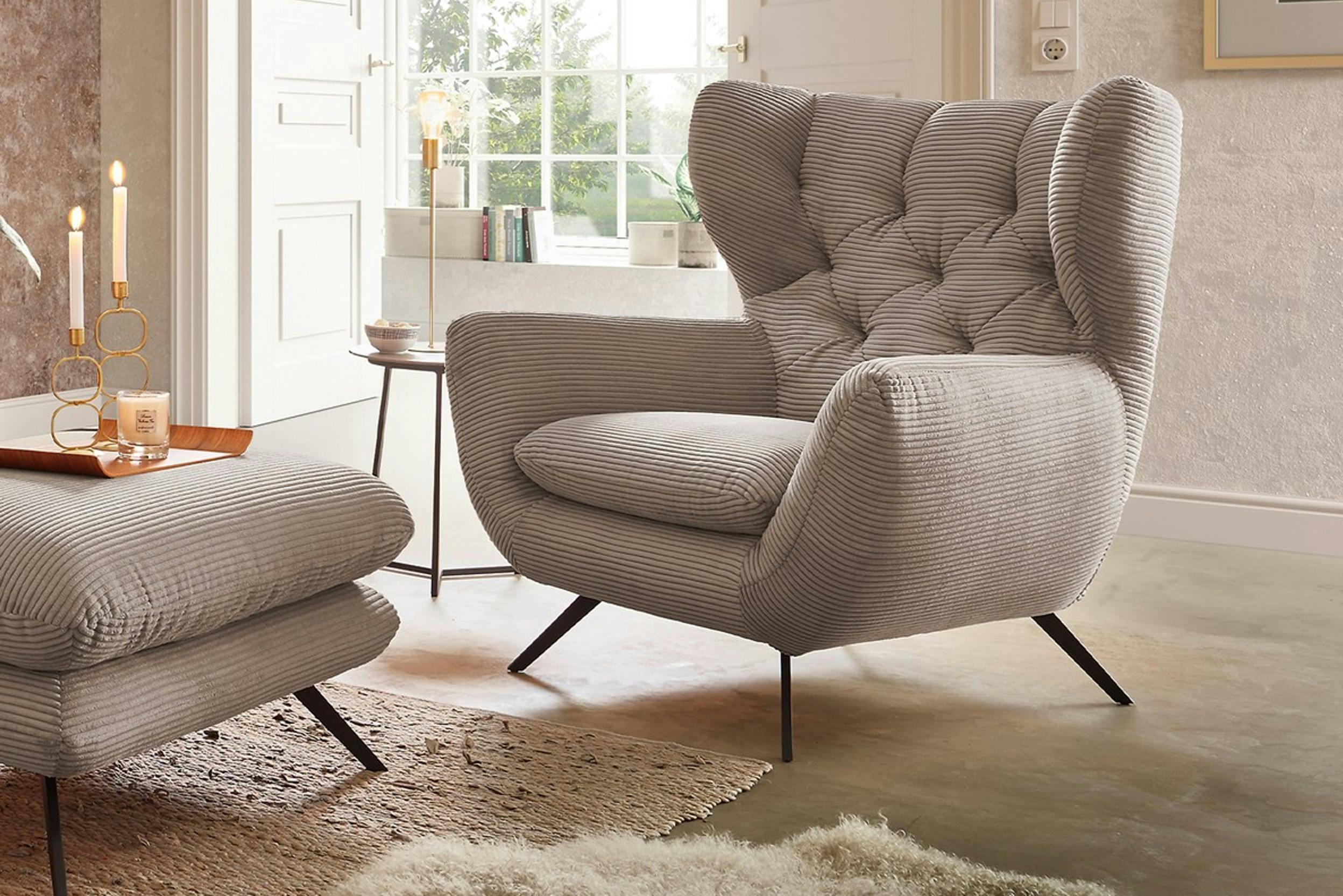 Cremefarbener Ohrensessel mit pasendem Fußhocker davor