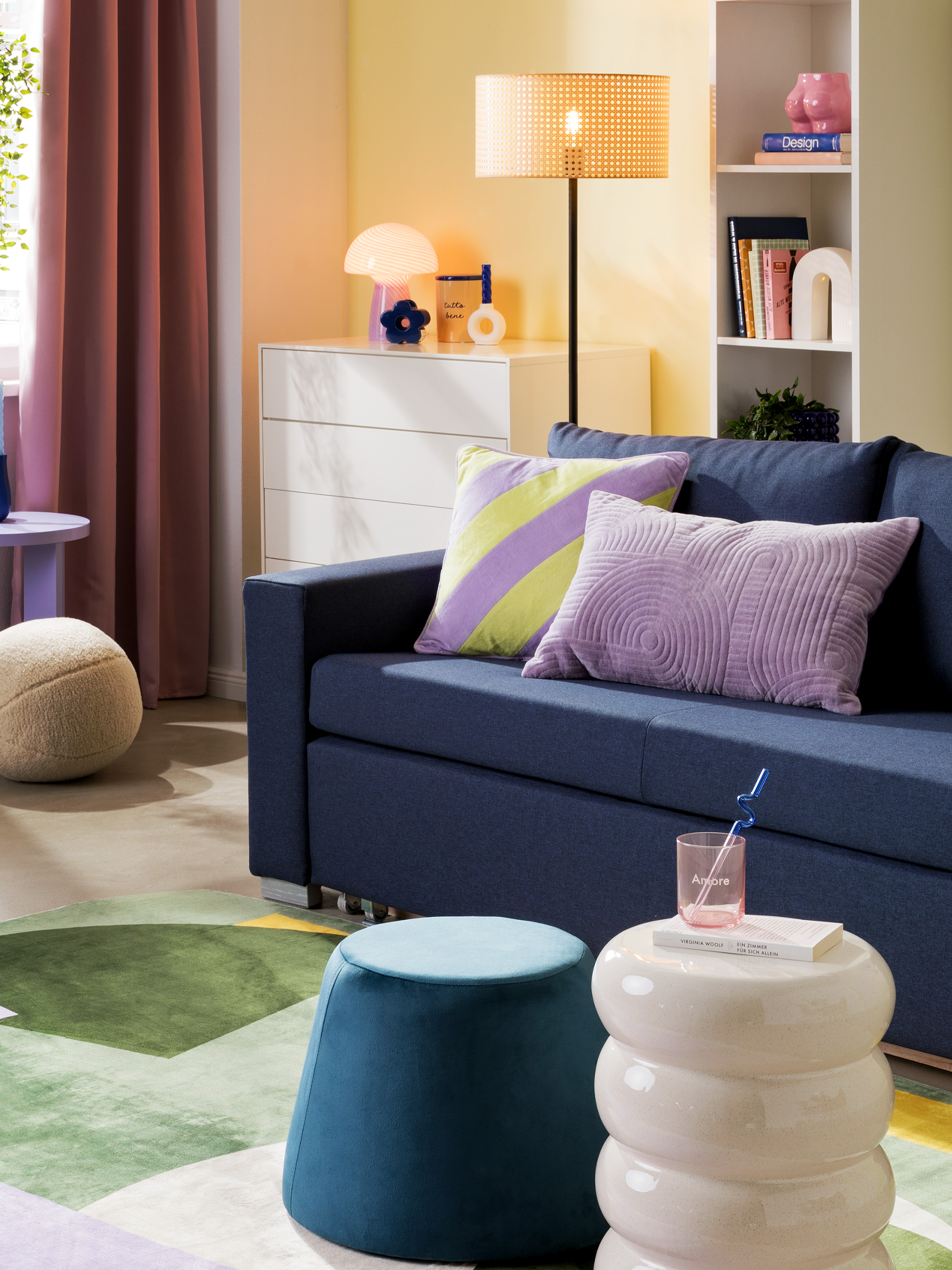 Dunkles, kompaktes Sofa mit bunten Beistelltischen und farbenfrohem Teppich.