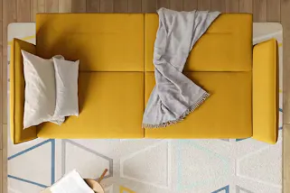 Ausklappbares, gelbes Schlafsofa mit weißen Kissen und beiger Decke.