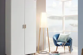 Weißer Kleiderschrank im Skandi-Stil mit stylisher Holzstehleuchte und einem schönen, blauen Sessel
