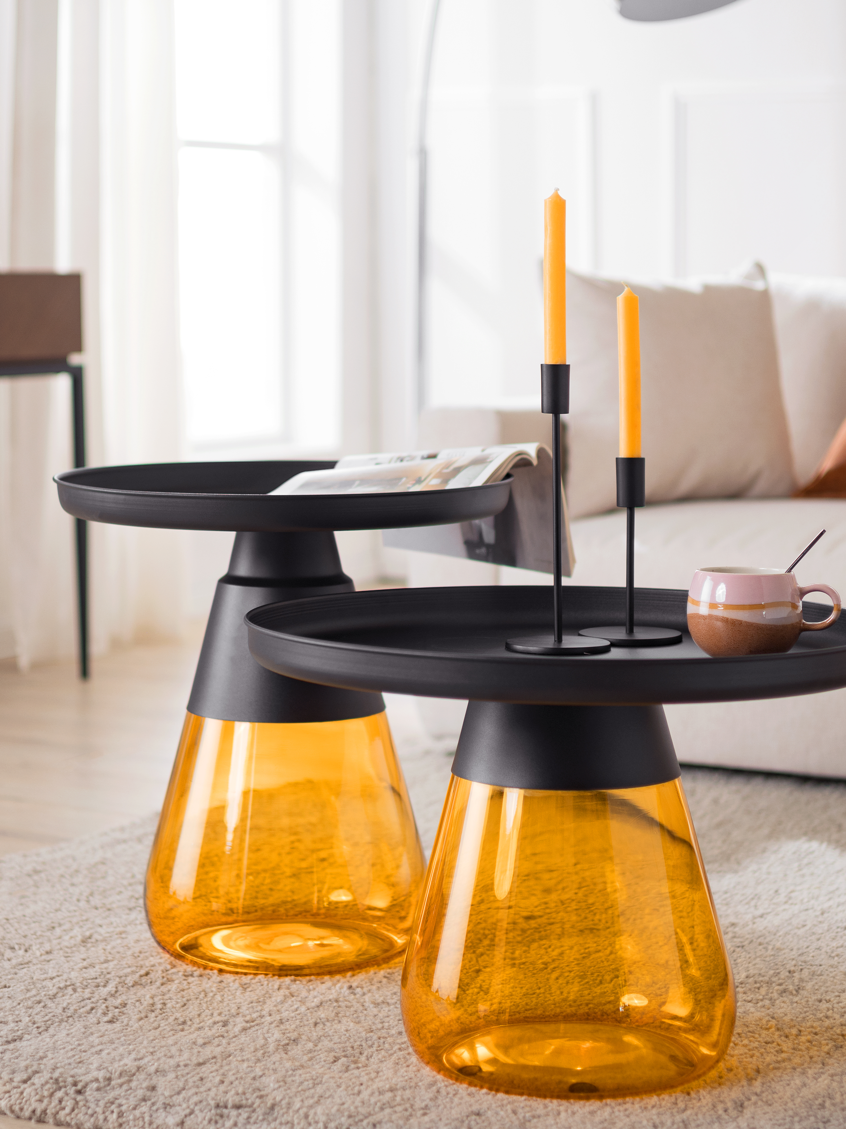 Couchtisch-Set mit gelbem Glaskorpus und schwarzer Ablagefläche.