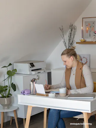 Arbeitszimmer im Skandi-Stil von Instagram Content Creator @missjule.home.living mit Schreibtisch und Regal aus weißen MDF-Platten und hellem Holz, farbenfroh dekoriert mit Vasen, Kerzenhaltern und bunten Wandbildern.